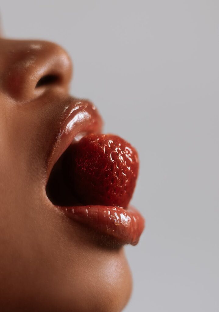 Artistic close-up of lips holding a strawberry, emphasizing sensuality and texture.